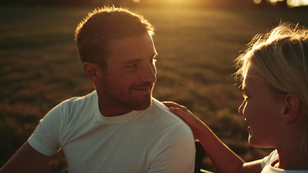 An adult child and their father sharing a quiet moment at golden hour