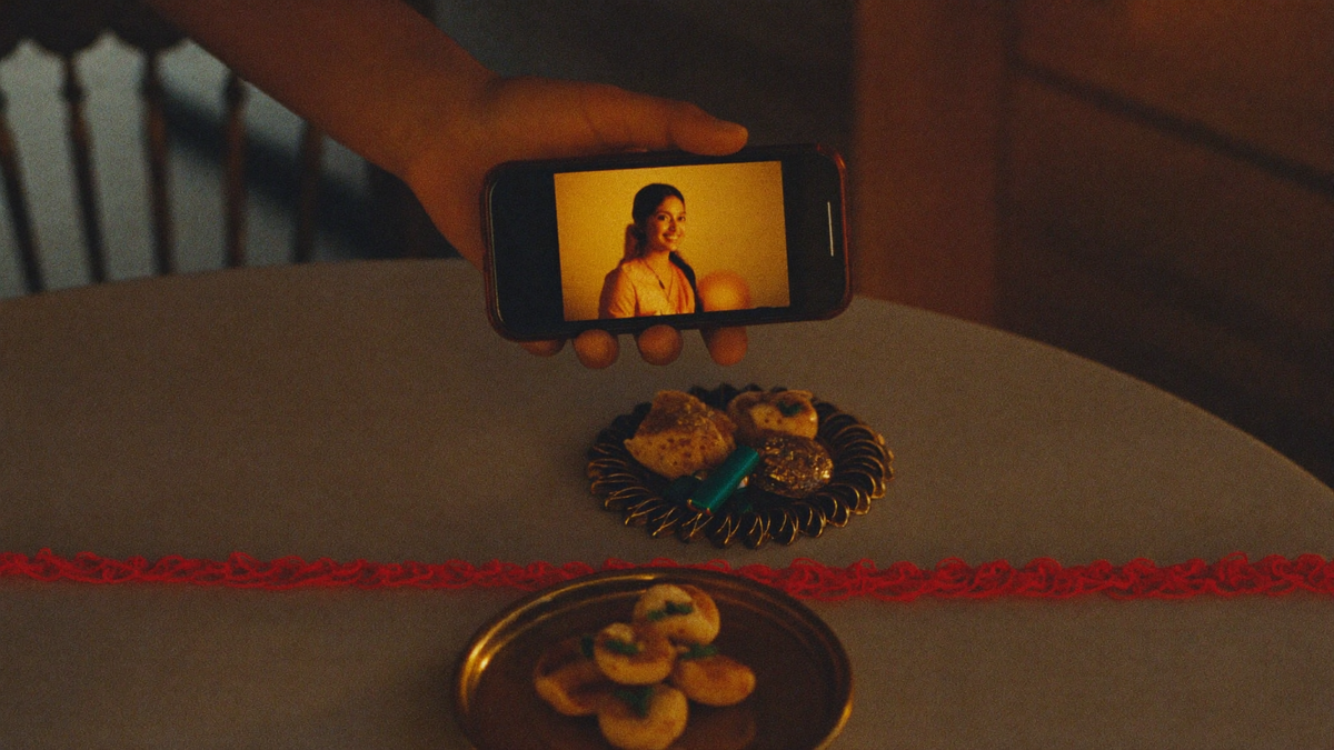 A Raksha Bandhan table with rakhi and sweets beside a video call